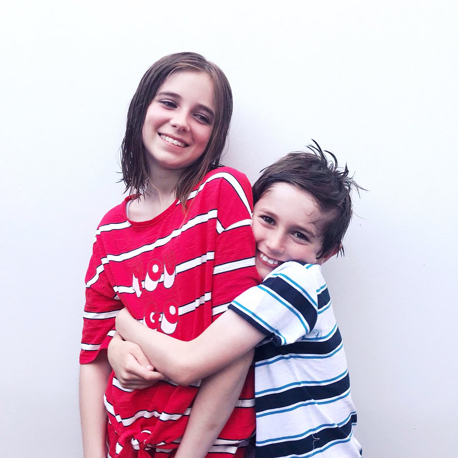 Brother and sister in pyjamas cuddling and smiling
