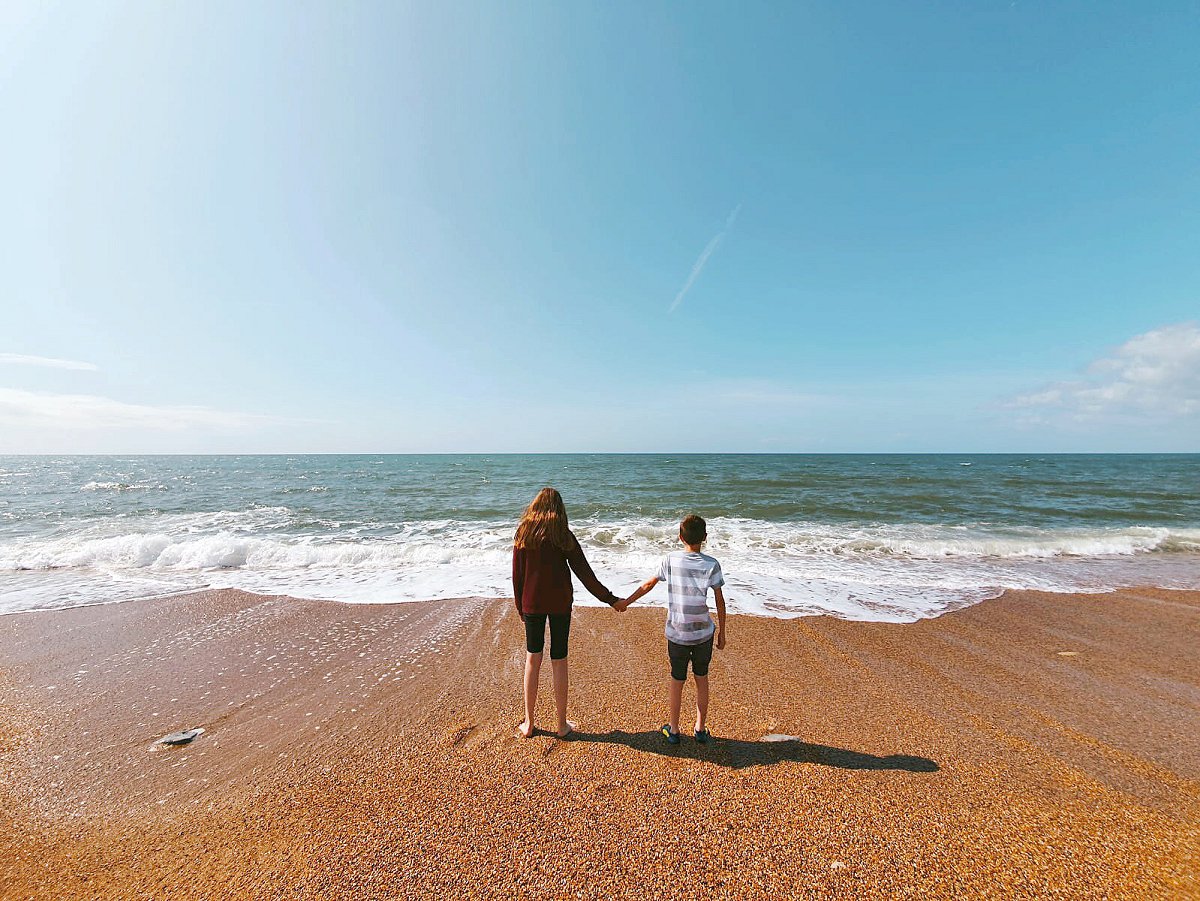 two children holding hands on a beach